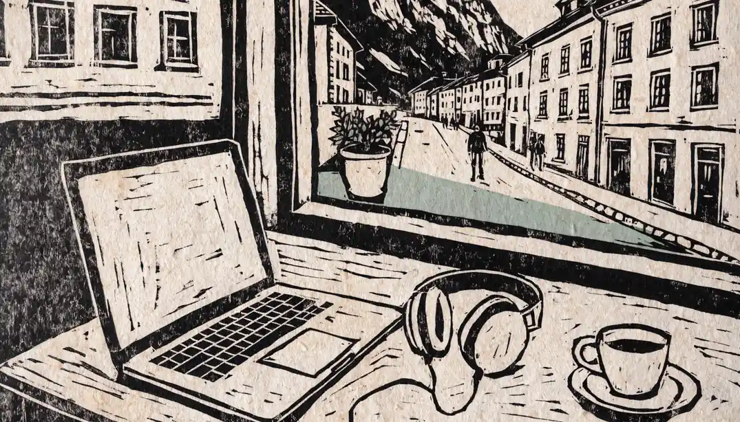 Laptop auf einem Schreibtisch mit Aussicht auf eine österreichische Alpenstadt.